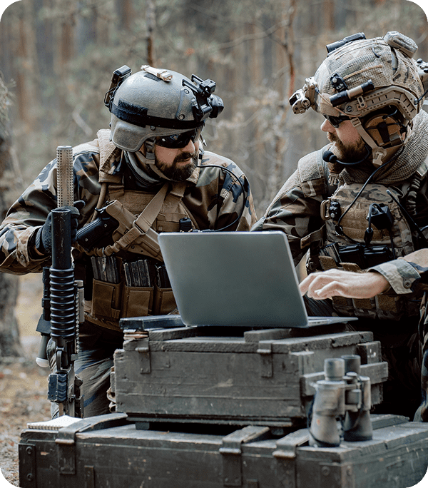 Soldiers using a laptop in a forest.